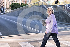 senior woman smiling happy crossing a city street
