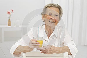 Senior Woman smilling while drinking Orange Juice