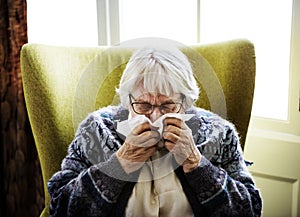 Senior woman sneezing on couch