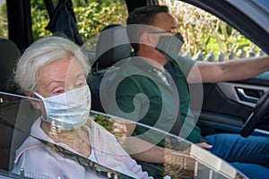 Senior woman and son with face mask driving in the car