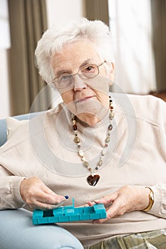 Senior Woman Sorting Medication Using Organiser