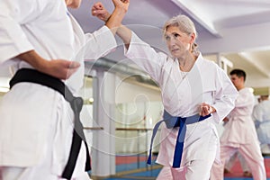 Senior woman sparring during group karate training