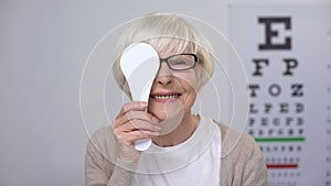 Senior woman in spectacles closing eye and smiling, proper lens diopter, checkup