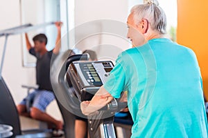 Senior woman spinning on bike in fitness gym club