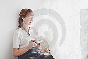 Senior woman standing against white wall