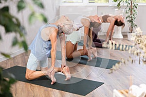 Senior woman standing in backbend asana Ustrasana in yoga studio