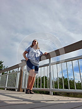 Senior Woman Standing Besides Bridge Railing