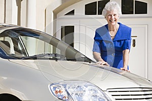 Senior woman standing next to new car