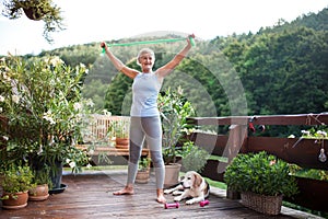 A senior woman standing outdoors on a terrace in summer, doing exercise.