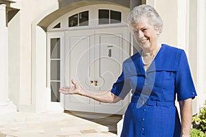 Senior woman standing outside home