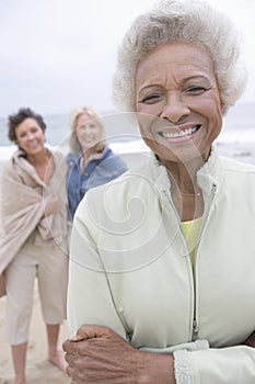 Senior Woman Stands In Fleece Jacket With Friends On Beach photo