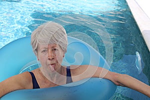 Senior woman sticking out tongue in swimming pool