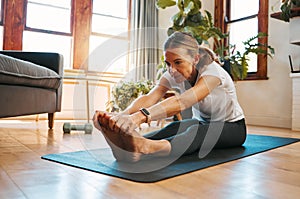 Senior woman, stretching and exercise in living room for fitness, cardio and wellness on yoga mat home training