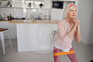 Senior woman stretching exercising equipment at cozy room