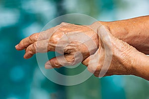 Senior woman stretching herself in bokeh blue swimming pool background, Close up & Macro shot, Selective focus, Healthcare concept