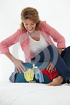 Senior woman struggling to shut suitcase