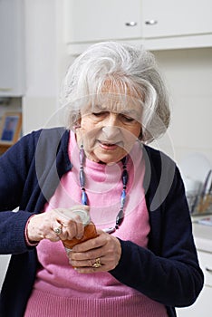 Senior Woman Struggling To Take Lid Off Jar