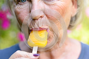 Senior woman sucking on an iced orange lolly