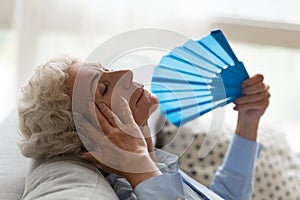 Senior woman suffer from hot weather using hand fan