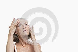 Senior woman suffering from headache against white background