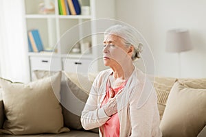 Senior woman suffering from heartache at home photo