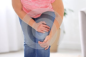 Senior woman suffering from knee pain at home