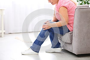 Senior woman suffering from knee pain at home, closeup.