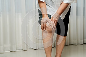 Senior woman suffering from knee pain at home, health problem concept