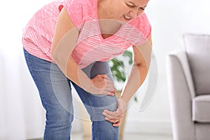 Senior woman suffering from knee pain at home