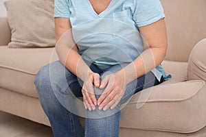 Senior woman suffering from knee pain at home