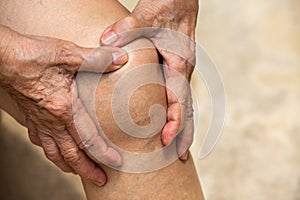 Senior woman suffering from knee pain sitting on chair, Massaging by her hand, Body concept
