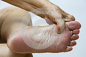 Senior woman suffering from left foot pain, Massaging by her hand in white background, Close up & Macro shot, Asian body skin part