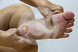 Senior woman suffering from left foot pain, Massaging by her hand in white background, Close up & Macro shot, Asian body skin part