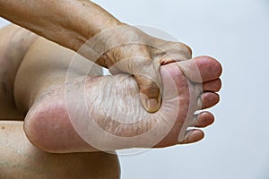 Senior woman suffering from left foot pain, Massaging by her hand in white background, Close up & Macro shot, Asian body skin part