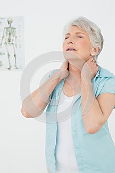 Senior woman suffering from neck pain in medical office