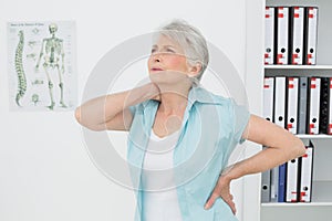 Senior woman suffering from neck pain in medical office