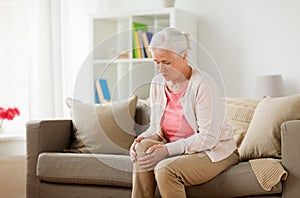 Senior woman suffering from pain in leg at home