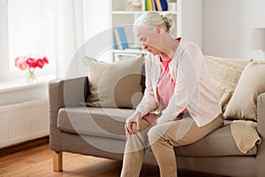 Senior woman suffering from pain in leg at home