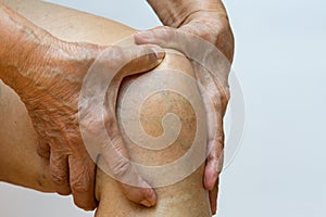 Senior woman suffering from right knee pain, Massaging by her hand in white background, Close up & Macro shot, Asian body skin