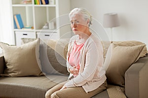 Senior woman suffering from stomach ache at home photo
