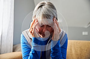 Senior Woman Suffering With Stress Or Headache At Home Holding Head In Pain