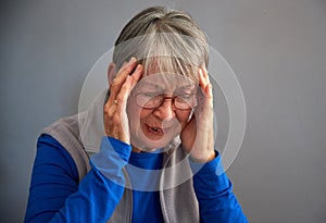 Senior Woman Suffering With Stress Or Headache At Home Holding Head In Pain