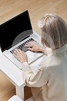 Senior woman surfing the net on laptop at home