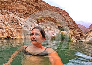 Senior woman swimming in clear water of Wadi Shab