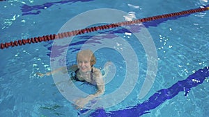 Senior woman swims in blue pool