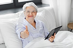 senior woman with tablet pc in bed at home bedroom