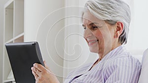 Senior woman with tablet pc in bed at home bedroom