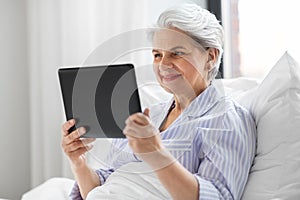 senior woman with tablet pc in bed at home bedroom