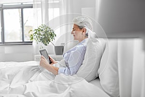 senior woman with tablet pc in bed at home bedroom