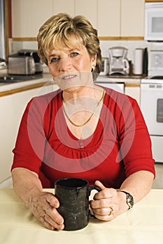 Senior woman taking a coffee break in her kitchen